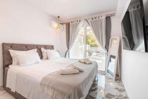 a white bedroom with a bed with towels on it at Punta Mare Villas in Karpathos