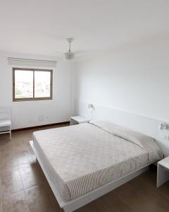 a white bedroom with a bed and two tables at Pousada do Norte, ilha do Fogo in Calheta