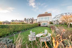 a yard with chairs and a table in front of a house at East Vows - Elie in Earlsferry