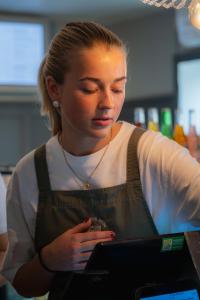 a woman wearing an apron looking at a laptop computer at Tre Små Rum i Trosa in Trosa +73 photos