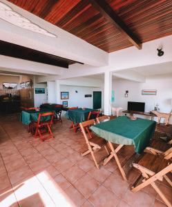 a room with tables and chairs and a flat screen tv at Mar Infinito Guest House in Arraial do Cabo