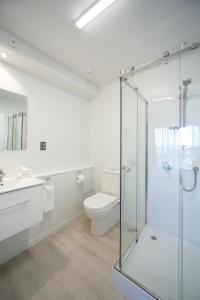 a bathroom with a toilet and a glass shower at Quest Petone in Lower Hutt