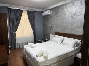 a bedroom with a white bed with towels on it at Over City Hostel in Margilan