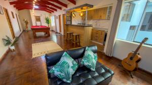 a living room with a leather couch and a guitar at Apart Hotel de Alegria in Cusco