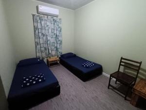 a small room with two beds and a chair at Kudat Beach House 4 in Kudat