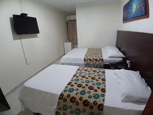 a hotel room with two beds and a flat screen tv at Hotel Paseo Colon in Barranquilla