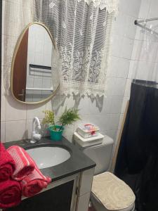 a bathroom with a sink and a mirror and a toilet at Flat na beira da praia in Maricá +18 photos