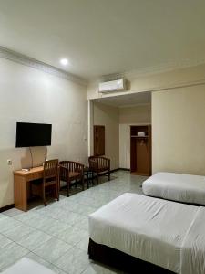 a hotel room with two beds and a flat screen tv at Aurora Hotel Kartini in Cirebon