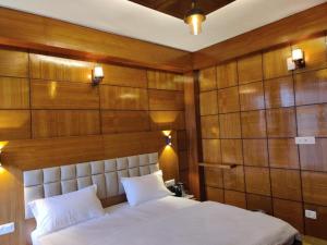 a bedroom with a large white bed with wooden walls at Hotel Mountain Nest in Nārkanda +17 photos