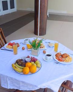 a table with plates of fruit and drinks on it at Pousada do Norte, ilha do Fogo in Calheta