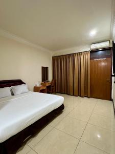 a bedroom with a large bed and a desk at Aurora Hotel Kartini in Cirebon +32 photos