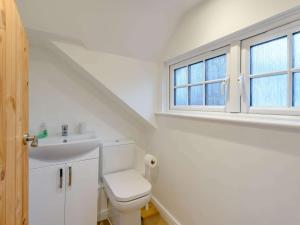 a bathroom with a toilet and a sink and two windows at 3 Bed in Wareham oc-81369 in Corfe Castle +14 photos