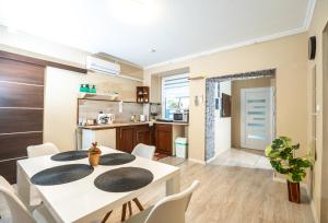 a kitchen and dining room with a white table and chairs at Royal Gold Apartman in Kiskunhalas