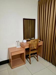 a wooden desk with a chair and a mirror at Aurora Hotel Kartini in Cirebon