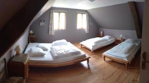 a attic bedroom with two beds and two windows at Gîte de la Gagée in Besmont