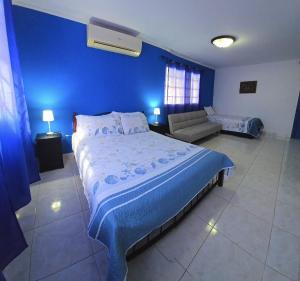 a blue bedroom with a large bed and a couch at Hostal Villa Mayte Coronado in Las Lajas +38 photos