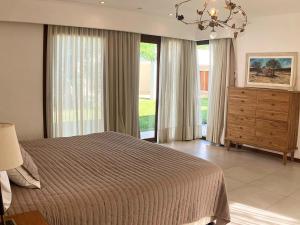 a bedroom with a bed and a dresser and windows at Casa Clara in Rufino