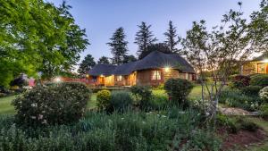 a house with a thatched roof in a garden at Ramabanta Trading Post in Setleketseng
