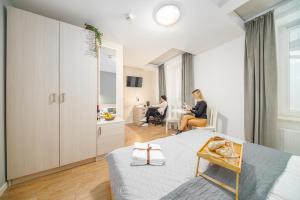 a room with a bed and two people sitting in chairs at S12 Boutique Residence - by Hosty in Krakow