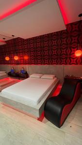a bedroom with a large bed and a black chair at Luxu's Motel in Tucano
