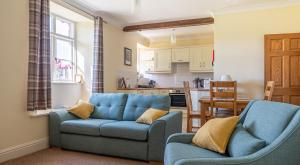 a living room with a blue couch and two chairs at Crummock at the Graythwaite Estate in Sawrey