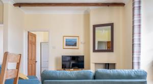 a living room with a blue couch and a tv at Crummock at the Graythwaite Estate in Sawrey