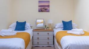 two twin beds in a room with a dresser at Crummock at the Graythwaite Estate in Sawrey