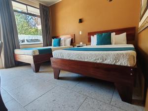 a bedroom with two beds and a window at Hotel Wilson Condega in Liberia
