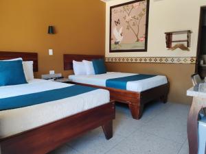 a hotel room with two beds with blue and white sheets at Hotel Wilson Condega in Liberia