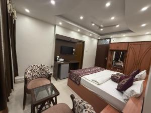 a bedroom with a bed and a chair and a television at Hotel Valentines in Prayagraj +7 photos
