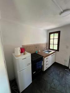 a small kitchen with a sink and a refrigerator at La Huella in Chascomús +25 photos