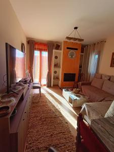 a living room with a couch and a television at Νύμφη Ηχώ, Θέα στα βουνά κάτω από το Ρολόι in Dimitsana