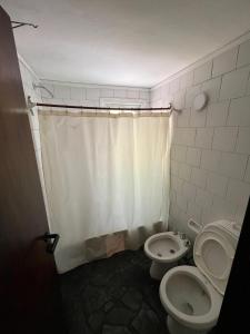 a bathroom with two toilets and a shower curtain at La Huella in Chascomús