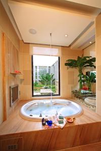 bañera grande en una habitación con ventana en Norway Forest Tamsui Motel, en Tamsui