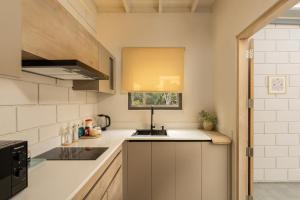 a kitchen with white cabinets and a sink and a window at Chaparrals Surf in Dickwella