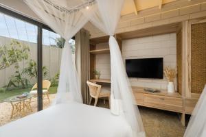 a bedroom with a tv and a bed with curtains at Chaparrals Surf in Dickwella