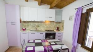 a kitchen with white cabinets and a table and a sink at Casa Andrea in Cefalù