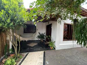 a small white house with a porch and trees at Casa Gabo in Serra