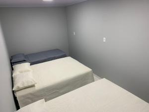 two beds in a small room with white walls at Casa com Spa aquecido em Itajuba in Barra Velha