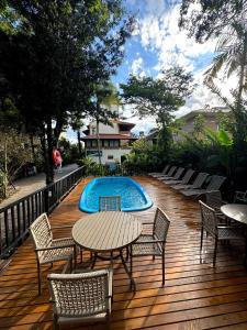 a deck with a table and chairs and a swimming pool at Hotel Natur Campeche in Florianópolis