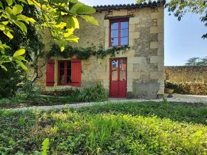 an old stone house with red doors and windows at Gîte de Marcoux, authentic and warme house in Saint-Laon