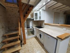 a kitchen with a stove and a washer and dryer at Gîte de Marcoux, authentic and warme house in Saint-Laon