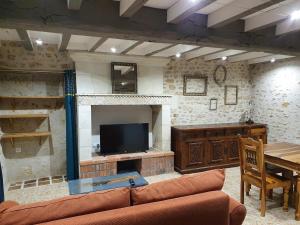 a living room with a couch and a television at Gîte de Marcoux, authentic and warme house in Saint-Laon +8 photos