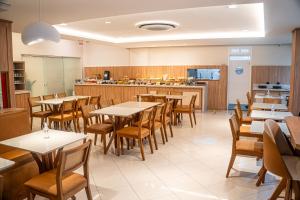 a restaurant with tables and chairs and a kitchen at Hotel Negrini in Balneário Camboriú