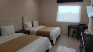a hotel room with two beds and a desk and a window at Hotel Del Viajero in Ciudad del Carmen