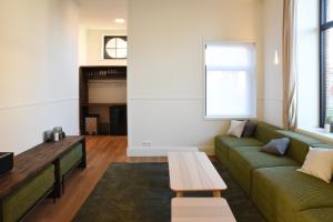a living room with a green couch and a table at Oud Tolkantoor in Alveringem