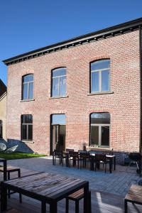 a brick building with tables and benches in front of it at Oud Tolkantoor in Alveringem