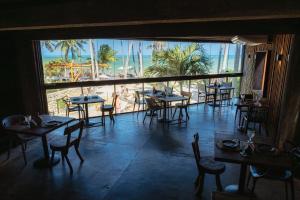 a restaurant with tables and chairs and a view of the ocean at Pedras Do Patacho Hotel Boutique Experience in Pôrto de Pedras