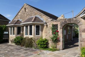 a stone house with an archway in a yard at Stanton Lodge Cottage - 2 bedrooms - sleeps 5 in Curbar