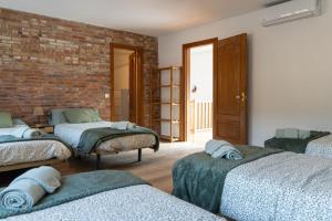 a room with three beds and a brick wall at Casa rural La Plana in Alcover